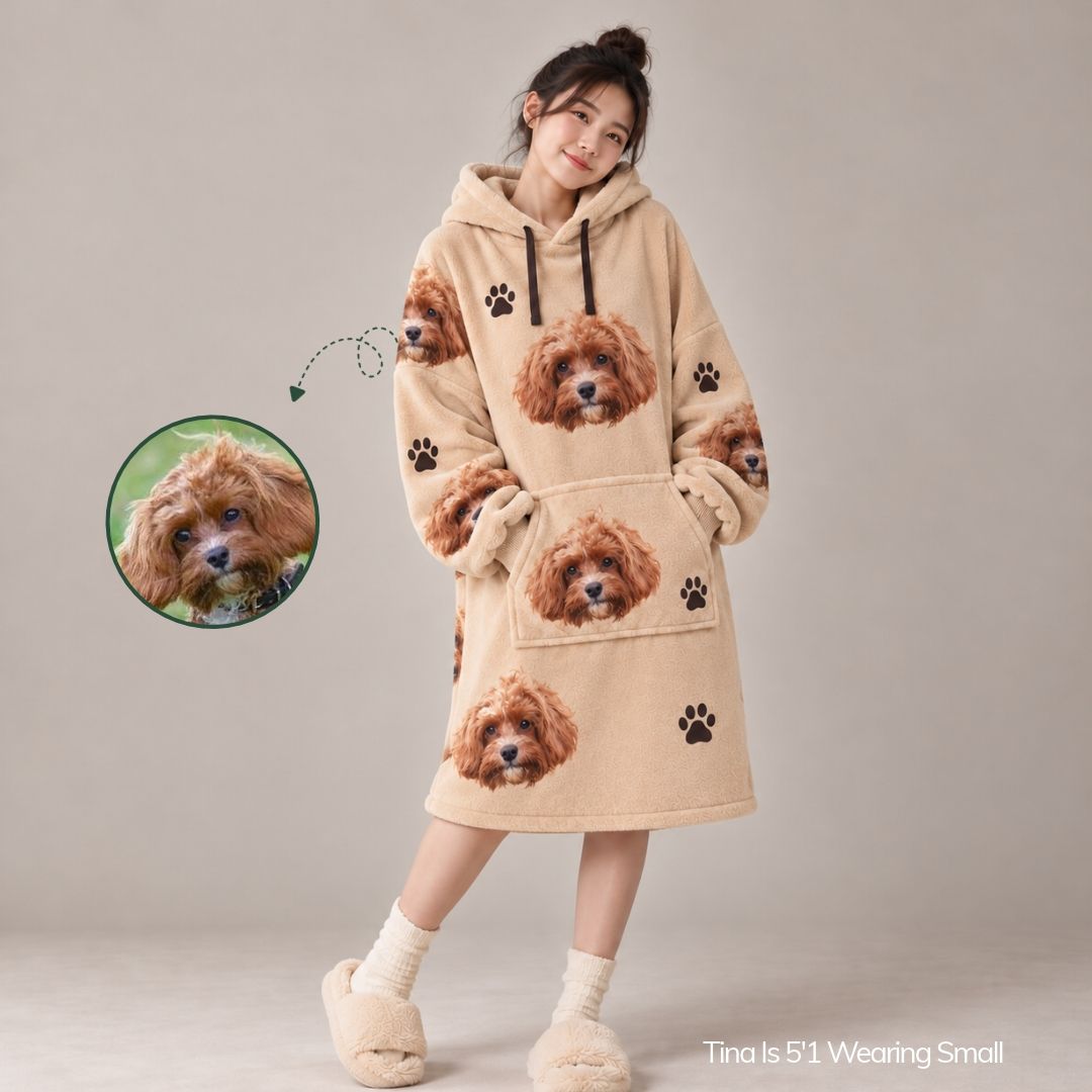 A woman models a beige oversized hoodie dress with a printed pattern of small brown dogs and black paw prints. A circular inset shows a small dog photo, with an arrow pointing to the dress pattern, and text at the bottom right reads 'Tina Is 5'1 Wearing Small'.