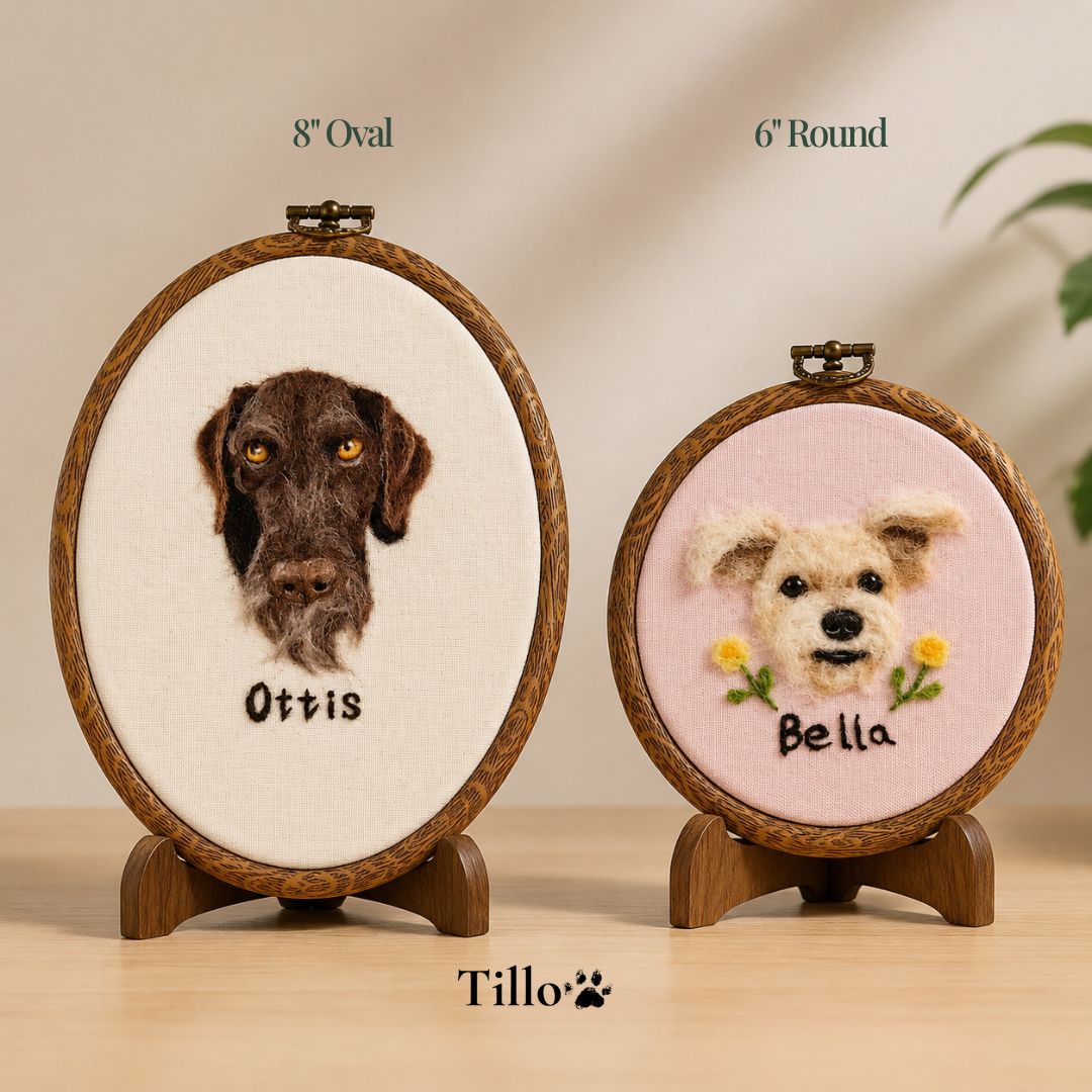 Two oval pet portrait embroidery hoops displayed on wooden stands on a tabletop. The larger left hoop is labeled 8" Oval and shows a dark brown dog portrait with the name Ottis on an off-white background.