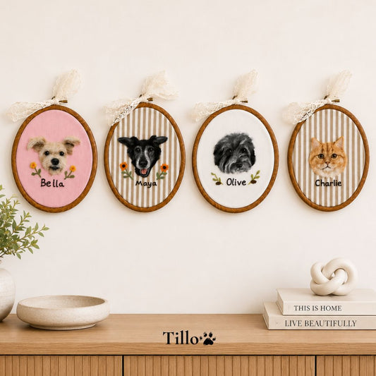 Four personalized pet portrait embroidery hoops displayed on a wall above a wooden console table. The hoops feature custom pet illustrations labeled Bella, Maya, Olive, and Charlie, each with a striped background and lace ribbon hangers.